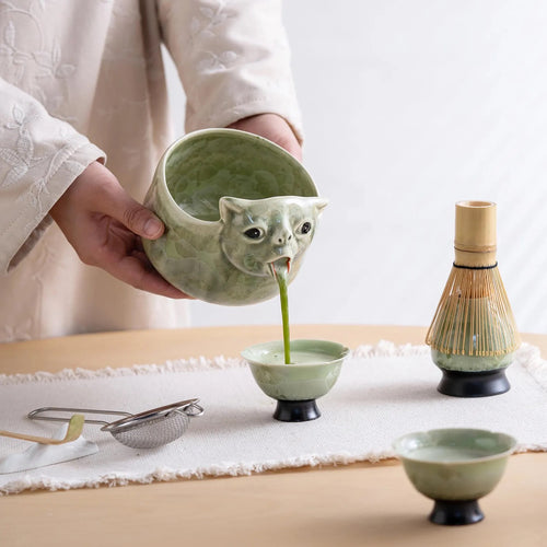 Matcha pouring from the cat's mouth spout into a cup